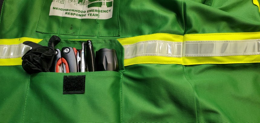 A picture of a NERT vest with a pen, marker, flashlight, and exam gloves in the pocket.